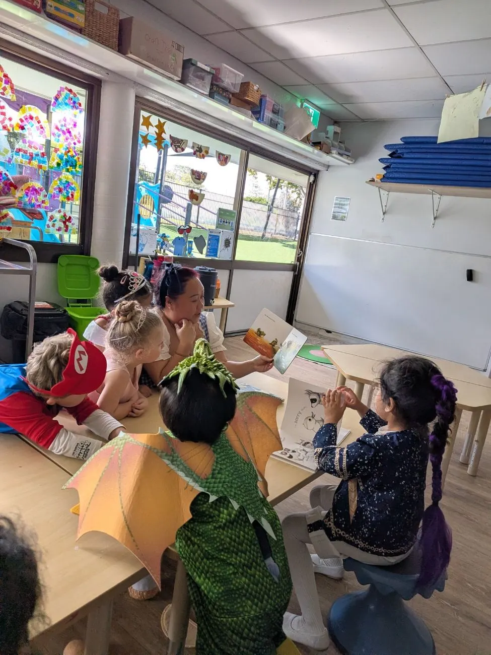 Children in dress-ups gathered around an educator reading a story
