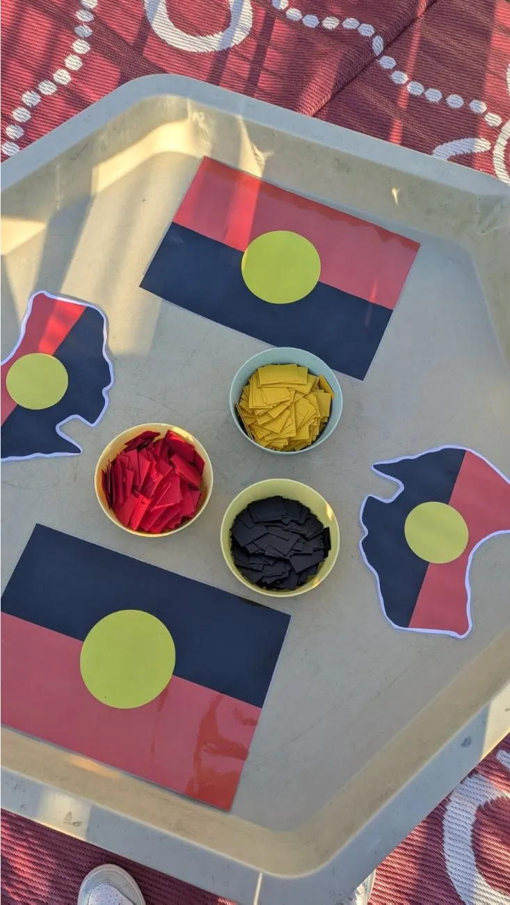 A tray set up with Aboriginal flag collage pieces in red, yellow and black