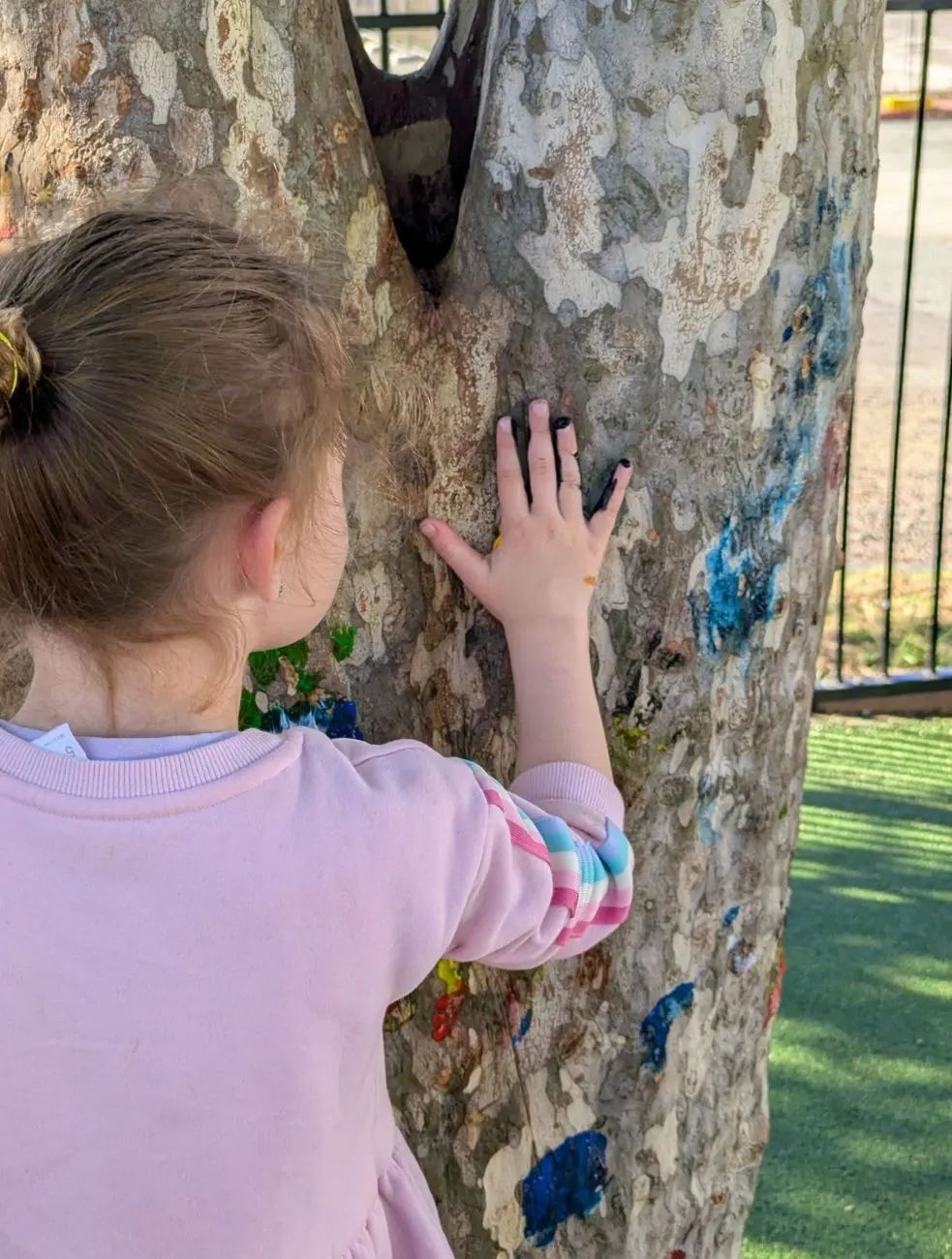 A child with her hand on the painted trunk of the yard tree