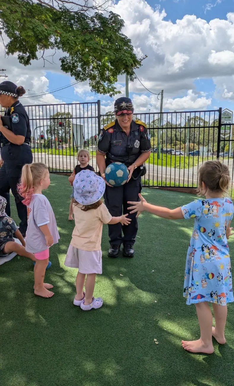 A police officer playing ball with the children in the yard