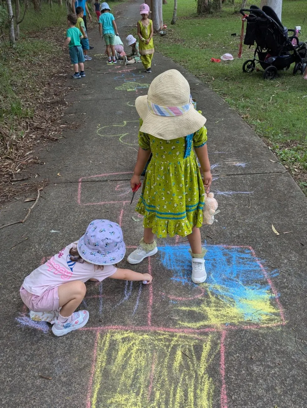 Children drawing with chalk along the path at Bush Kindy