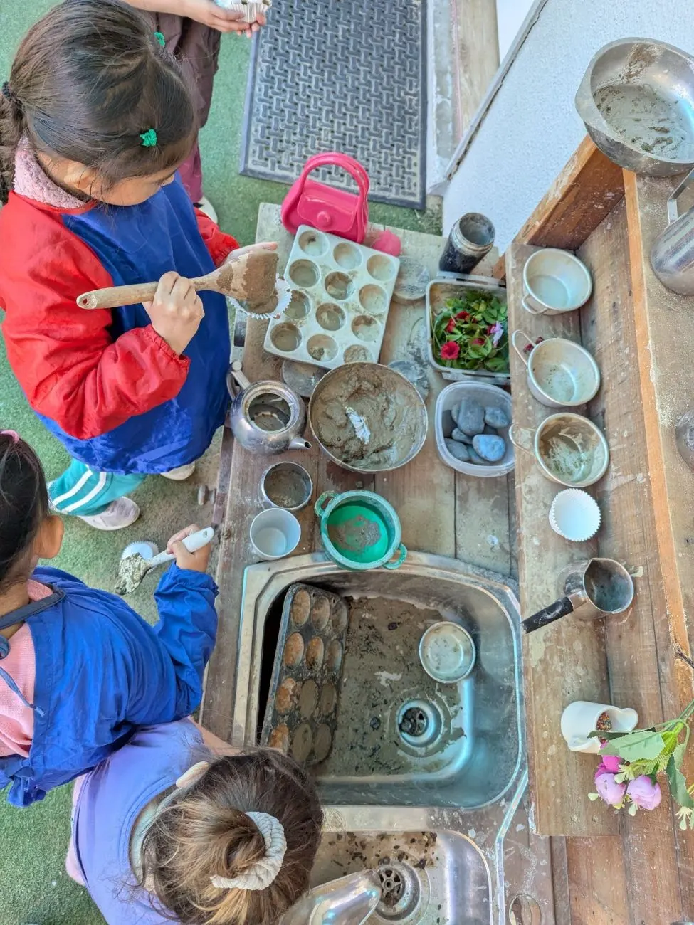 Children baking mud cupcakes at the mud kitchen