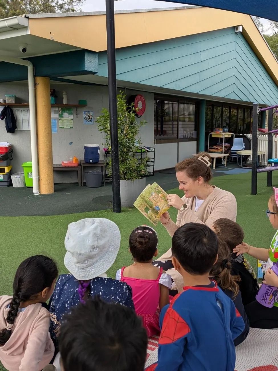 The kindy group listening to a story on the mat outside