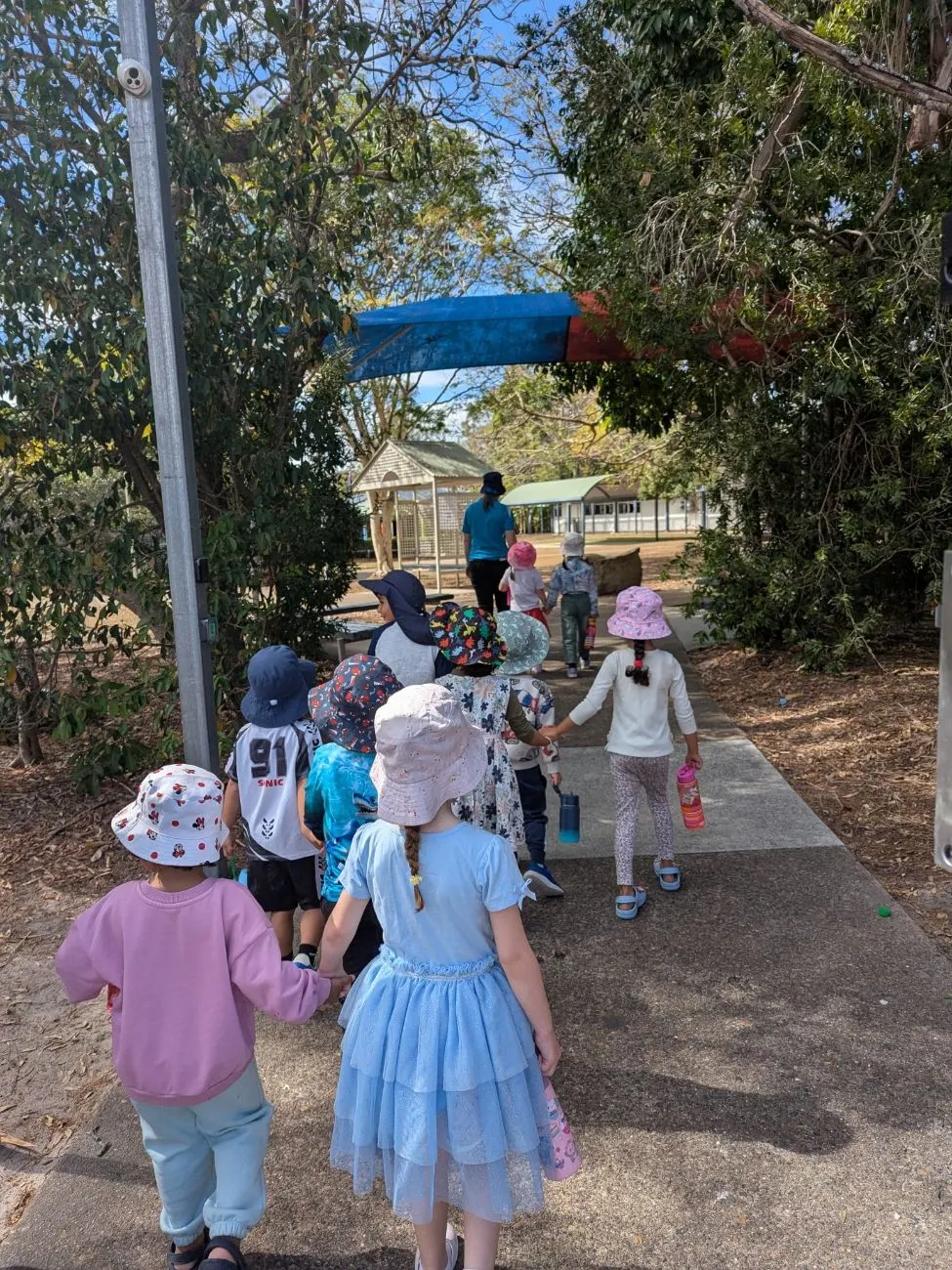 Kindy children walking hand in hand into a local school ground