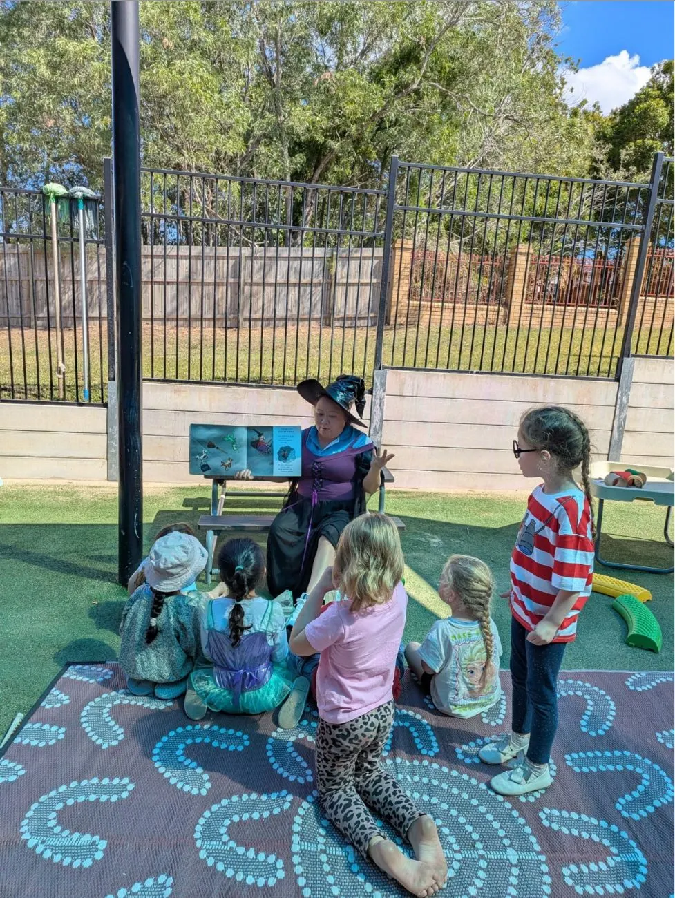 An educator in costume reading a story to children outside