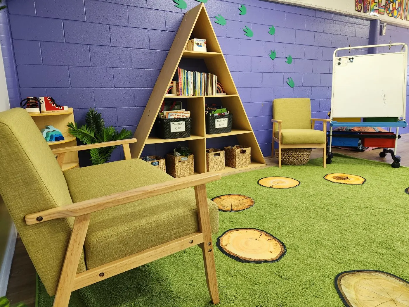 The kindergarten reading corner, with an A-frame book shelf, armchairs and a green rug