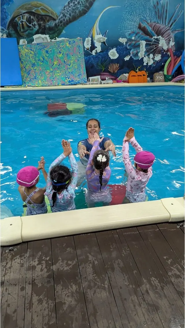 Children in the pool with their swim teacher during a lesson