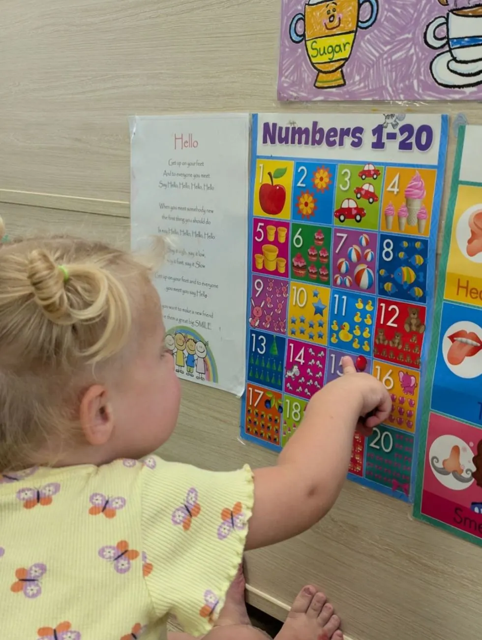 A toddler pointing to the numbers chart on the wall
