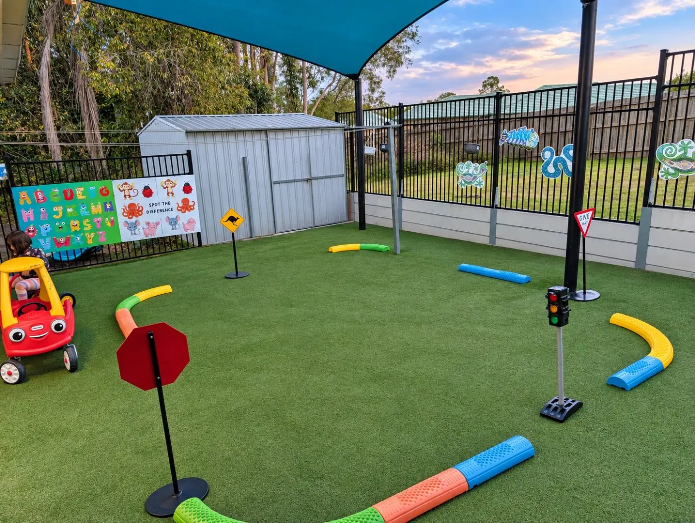 The toddler yard set up as a mini road track with stop signs, traffic lights and a ride-on car