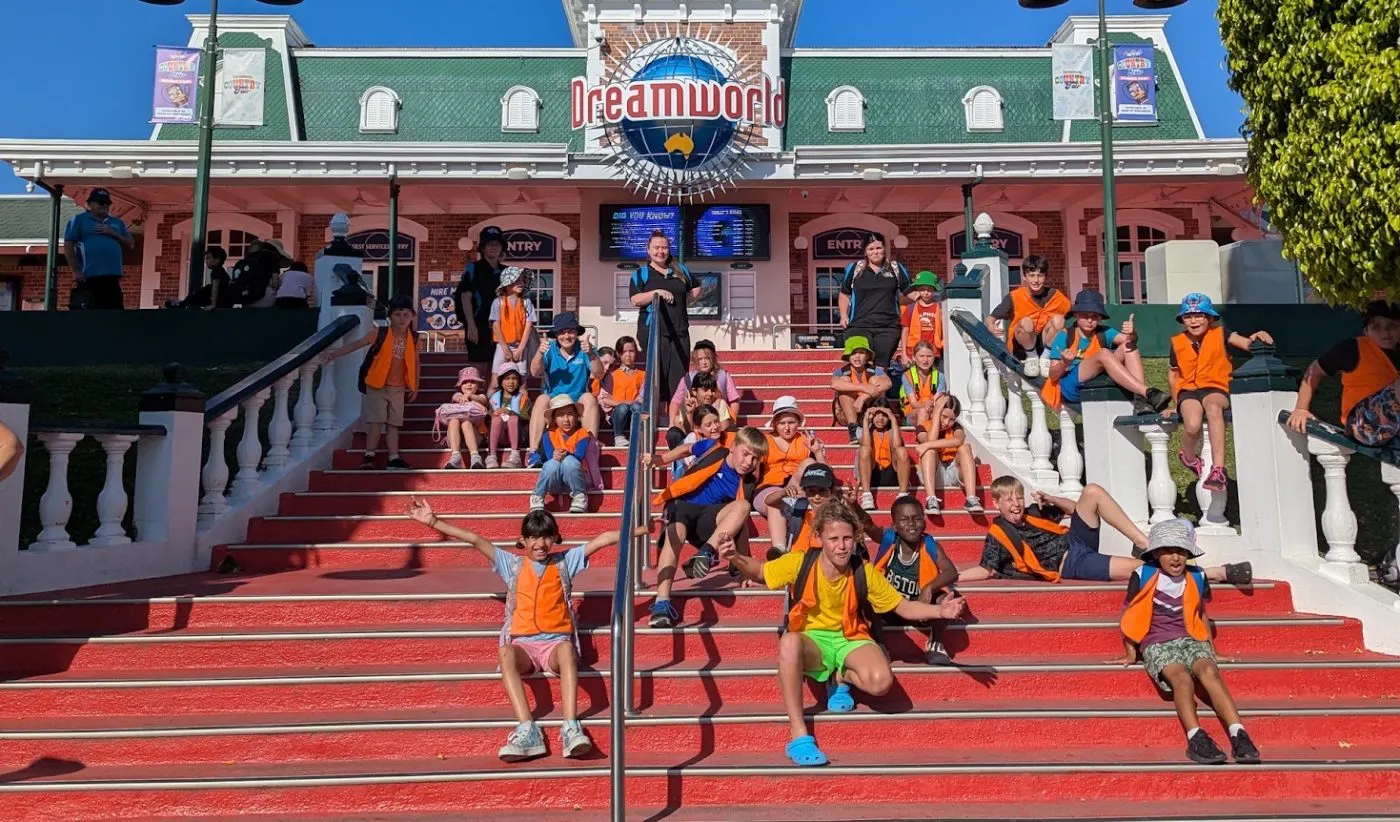 Vacation care children in orange safety vests on the steps at the Dreamworld entrance
