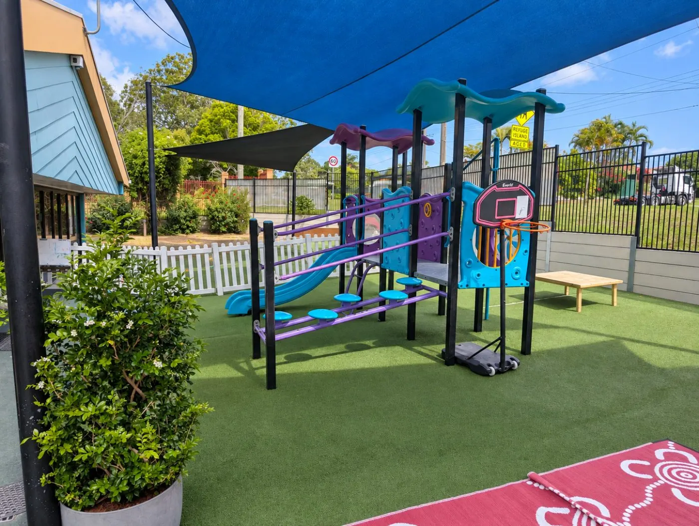 The playground under the shade sails, with the climbing frame, slide and basketball hoop